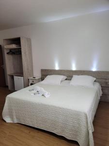 a bedroom with a large white bed with towels on it at Hotel Vila Germânica in Blumenau