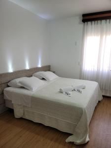 uma cama com lençóis brancos e almofadas num quarto em Hotel Vila Germânica em Blumenau