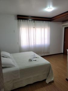 a bedroom with a bed and a large window at Hotel Vila Germânica in Blumenau