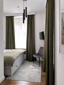 a bedroom with a bed and a chair and a window at Apartament Miła 2 Lądek-Zdrój in Lądek-Zdrój