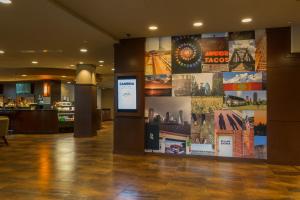 a lobby with a large wall with posters on it at Cambria Hotel Plano - Frisco in Plano
