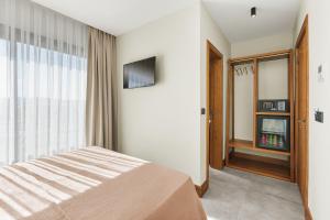 a bedroom with a bed and a tv and a window at Meruno Alaçatı in Çeşme