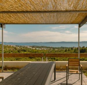 ein Holztisch mit Bank und Strohdach in der Unterkunft Villa Pava in Zadar