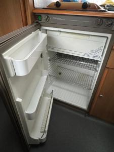 Camping Van في كيفلافيك: ثلاجة فارغة وبابها مفتوح في مطبخ
