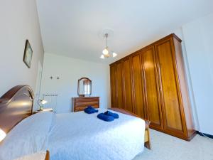 - une chambre avec un grand lit blanc et une armoire en bois dans l'établissement SANREMO Mare e Relax - Affittasi Casa Illiade con parcheggio libero, à Sanremo