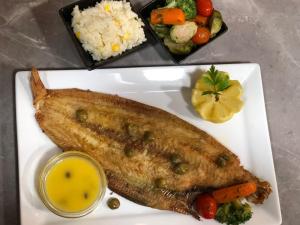 a fish on a plate with rice and vegetables at Catrass Oualidia Apartments in Oualidia +26 photos