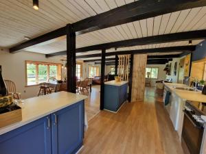 a kitchen with blue cabinets and a living room at Family-Friendly Coastal Cottage in Henne