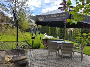un patio con mesa, sillas y sombrilla en Szczawnica Residence "Nad Zdrojami" - In the Heart of Recreation 691-739-603 en Szczawnica