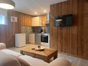 un salon avec un canapé et une télévision sur un mur dans l'établissement Hohneck - Studio de Montagne La Bresse / Gerardmer, à La Bresse