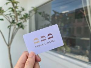 eine Hand mit einer weißen Karte mit einem dreieckigen Haus in der Unterkunft Triple D Hotel in Betong