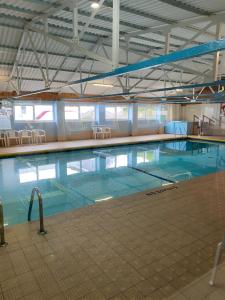 a large swimming pool with blue water in a building at 44 Gower holiday village Ty Gŵyr Cosy 2 bedroom Chalet in Swansea