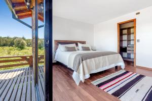 um quarto com uma cama e uma varanda em Orilla de Lago con Hot Tub, parrilla y vistas em Puyehue