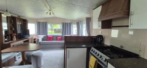 a kitchen with a stove top oven next to a living room at Excellent Static Caravan in Shanklin