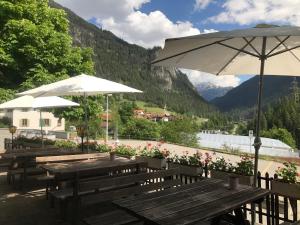 a group of wooden benches with umbrellas and flowers at Hotel Schöntal in Filisur