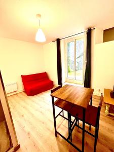 a living room with a red couch and a wooden table at Appartement avec terrasse au coeur d'Aurillac in Aurillac +7 photos