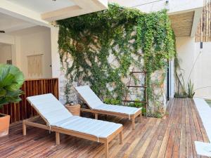 2 sillas en un patio con una pared cubierta de hiedra en Casa Ita Surf - Adults Only, en Puerto Escondido