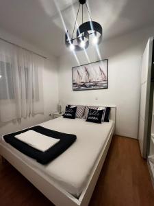 sypialnia z dużym białym łóżkiem z czarnymi poduszkami w obiekcie Apartments Kapetanovi Dvori w Trogirze