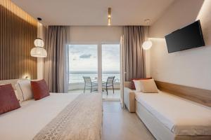 a hotel room with two beds and a view of the ocean at Anna Beach Suites in Limenaria +95 photos