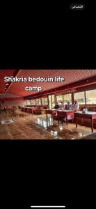 Shakria Bedouin Life Camp في وادي رم: مجموعة من الناس يجلسون على طاولات النزهة في مبنى