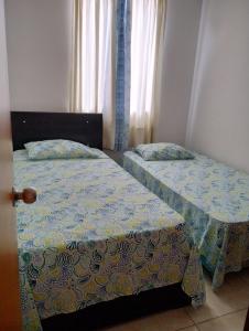 2 camas individuales en una habitación con ventana en Alojamiento en Cúcuta al lado del Centro Comercial Jardín Plaza, en Cúcuta