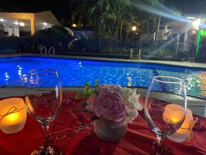 a table with two wine glasses and a vase of flowers at Hotel Villa Ricaurte in Girardot