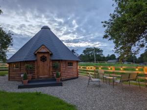 a cabin with a black roof and chairs and a fence at Apple blossom glamping in Kilkenny