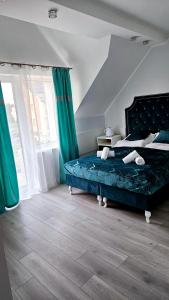 1 dormitorio con 1 cama con sábanas azules y cortinas verdes en Solar Bed & Breakfast, en Karwia