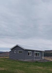 uma casa cinzenta no meio de um campo em Tungukot sumarhús em Akureyri