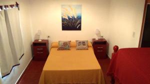 a bedroom with a bed and two night stands and a painting at Nature, comfort, and authenticity in the Salta countryside in Vaqueros