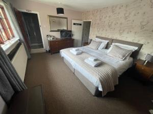 a bedroom with a large bed with towels on it at The Swan Inn in Monks Eleigh