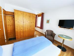 een slaapkamer met een bed, een tv en een stoel bij Hotel Schöntal in Filisur