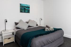 a bedroom with a bed with a green blanket at Eleven_at_Mauao in Mount Maunganui
