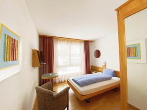 Schlafzimmer mit einem Bett, einem Tisch und einem Fenster in der Unterkunft Hotel Schöntal in Filisur