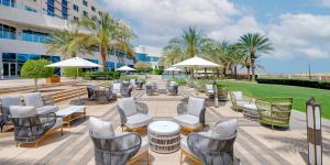 un patio con sedie, tavoli e ombrelloni di Crowne Plaza Muscat OCEC by IHG a Mascate
