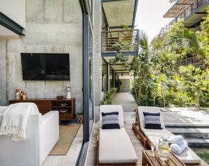 eine Außenterrasse mit weißen Möbeln und einem Fernseher in der Unterkunft Amazing 1BR Swim Up Cenote Gym in Tulum