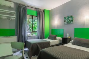 Una habitación con 2 camas y una ventana con verde en Hostal Tropical en Almuñécar