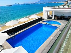 una piscina junto al océano con sombrillas en Hotel Star, en Manzanillo