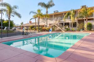 una piscina frente a un edificio con palmeras en Best Western Plus Hill House, en Bakersfield