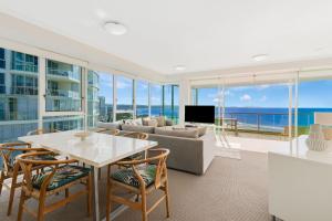 Una sala de estar con un sofá, una mesa y sillas. en Reflections On The Sea Unit 1501, en Gold Coast