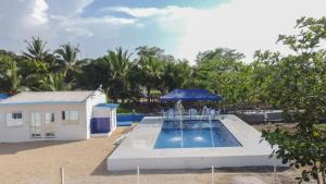 a swimming pool with a blue umbrella next to a building at Cabaña Palma Azul in Coveñas