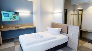 a small room with a white bed and a desk at Median Hotel Hannover Lehrte in Lehrte