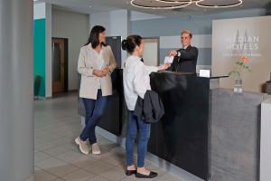 three people standing at a counter in an office at Median Hotel Hannover Messe in Hannover