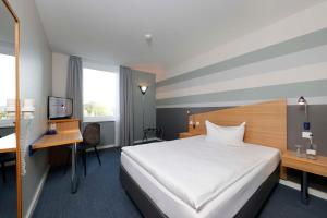 ein Hotelzimmer mit einem großen Bett und einem Schreibtisch in der Unterkunft Median Hotel Hannover Messe in Hannover