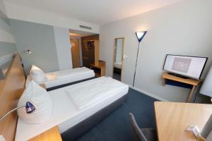 a hotel room with two beds and a flat screen tv at Median Hotel Hannover Messe in Hannover +52 photos