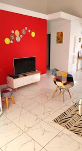 Maison Indép, Spa, Mer, Jardin, Bien-être في لي تروا زيليه: غرفة معيشة مع جدار احمر مع تلفزيون بشاشة مسطحة