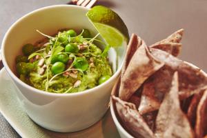 a bowl of guacamole with chips and a salad at The Emory in London