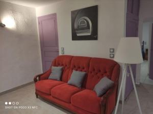 a red couch in a living room with a purple door at Charmante maison de village cessenon sur Orb in Cessenon