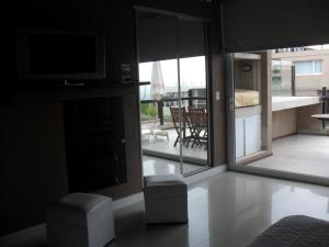 a living room with a television and a view of a patio at Linda Bay Spa de Mar in Mar de las Pampas