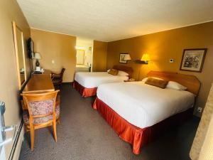 ein Hotelzimmer mit 2 Betten und einem Schreibtisch in der Unterkunft Travelodge by Wyndham Moose Jaw in Moose Jaw