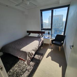 um quarto com uma cama, uma cadeira e uma janela em Bedroom & Private Bathroom in Modern Inner Brisbane Apartment em Brisbane